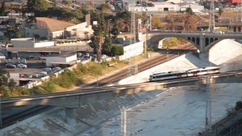 Train moving across waterway into city Stock Footage