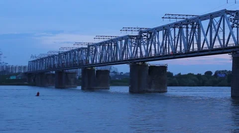 Train moving ahead on overpass bridge against night river. Stock Footage 64592785