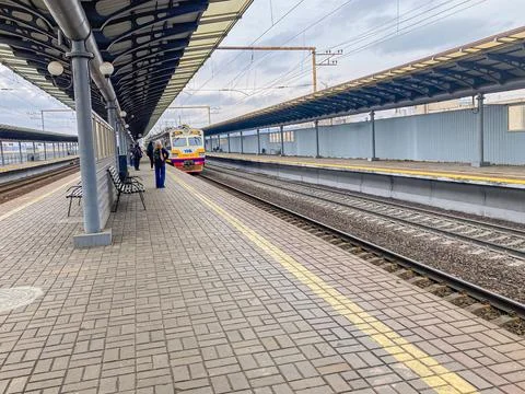 A train is parked at a red brick platform with safety markings Individuals ar Photos