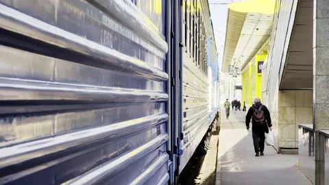 Train parked at station platform on sunny day, passenger walking along railway Stock Footage 342230979