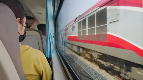 Train passenger sitting by the window of the train watching the outside scene Stock Footage 239985793
