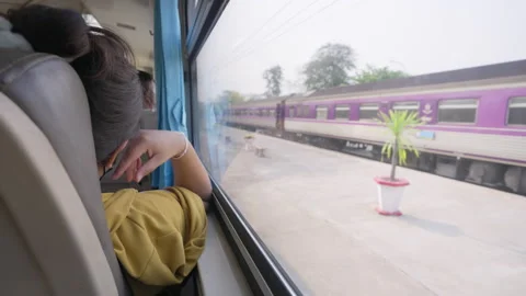 Train passenger sitting by the window of the train watching the outside scene Stock Footage 239986032