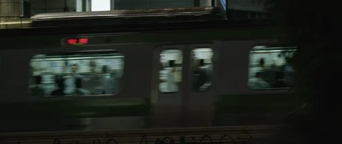 Train with passengers passing through city during night, banners in back, Tokyo Stock Footage 136124880