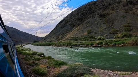 The train passes a large river in the mountains Stock Footage 282370957