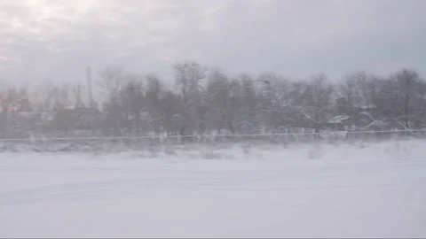 The train passes through the countryside with snow-covered buildings and trees Stock Footage 195104401
