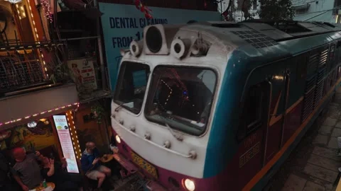 A train passes through Hanoi Train Street residents visitors sit close to tracks Stock Footage 330037651