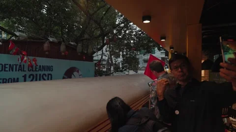 A train passes through Hanoi Train Street residents visitors sit close to tracks Stock Footage 330037738