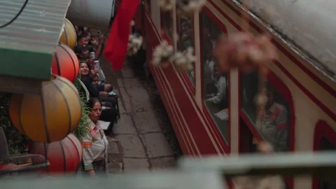 A train passes through Hanoi Train Street residents visitors sit close to tracks Stock Footage 330037982