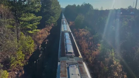 A train passes under a bridge on a bright morning in Georgia Stock Footage 147096543