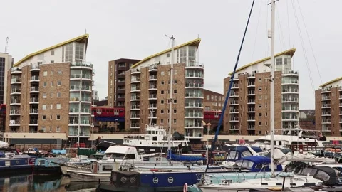 Train passing behind four identical buildings. Port with boats in front. Stock Footage 239430271