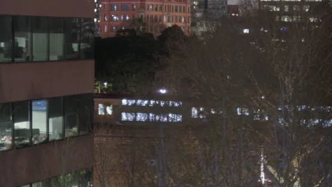 Train Passing Between Office Buildings at Dusk with Upward Pan Stock Footage 314944213