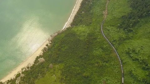 Train passing by it against the backdrop of green mountains and the sea. Stock Footage 128278643
