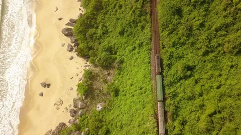 Train passing by it against the backdrop of green mountains and the sea. Video stock 128278792