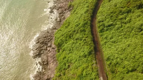 Train passing by it against the backdrop of green mountains and the sea. Stock Footage 128278820