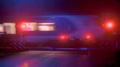 Train passing misty railroad crossing at night Stock Footage 165286295
