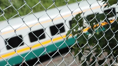 Train passing shot through fence, close tight shot, gray yellow and blue Stock Footage 248249061