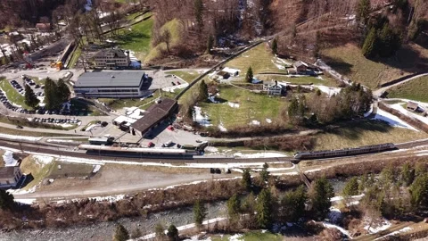 Train passing small alpine station Видео 332134555