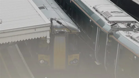 Train passing stationary train in station - misty morning. London Stock Footage 93209962