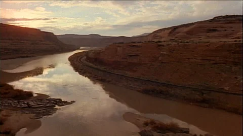 Train passing through canyon with clouds reflecting in water Stock Footage 29806356