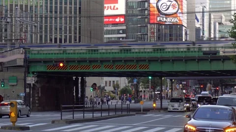 Train Passing Through City Center of Tokyo With Cars and Pedestrians Below Stock Footage 269150572
