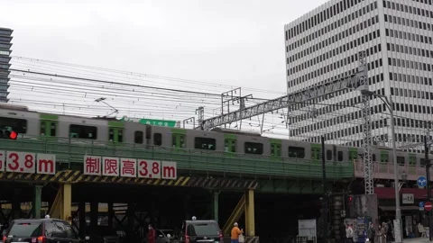 Train passing through downtown Tokyo with cars driving under a bridge Stock Footage 305674861