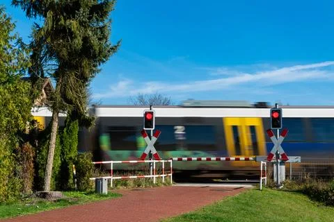 Train passing through level crossing on a clear summer day Stockfoto's