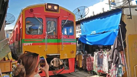 The train is passing through the Maeklong Railway market. 動画素材 119617703