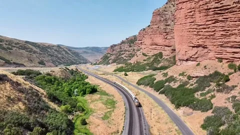 Train Passing Through Mountainous Railroad with Rocky Landscape Stock Footage 285158753