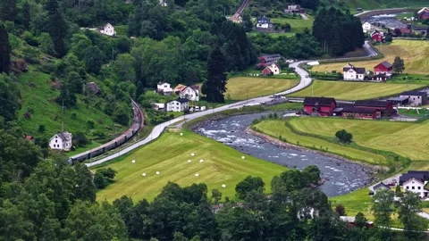 Train Passing Through Scenic Valley With River and Village Houses in Flam Stock Footage 341539178
