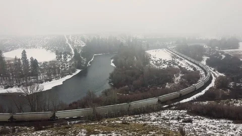 Train passing through snow covered valley along river Stock Footage 124616207