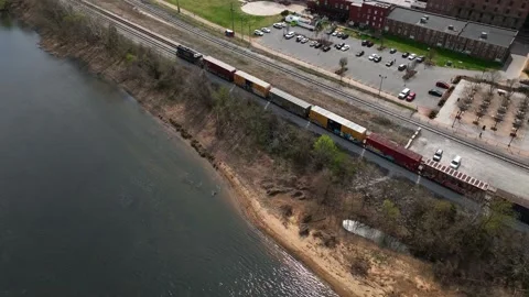 Train passing through town in Lynchburg, VA beside James River Stock Footage 237468277