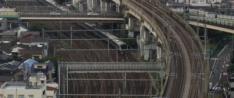 Train passing through train station on tracks, surrounded with poles, Tokyo Stock Footage 136125236