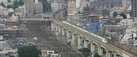 Train passing through train station on tracks, city in background, Tokyo Stock Footage 136125393