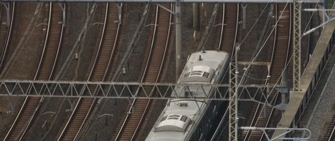 Train passing through train station on tracks, surrounded with poles, Tokyo Stock Footage 136125924