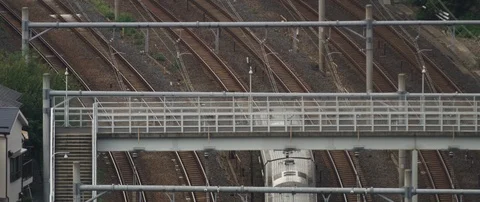 Train passing through train station on tracks, surrounded with poles, Tokyo Stock Footage 136127348
