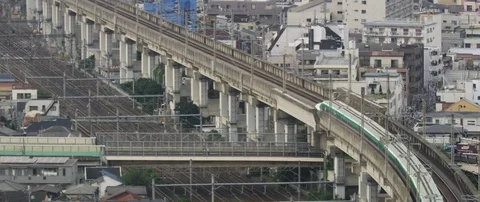 Train passing through train station on tracks, surrounded with poles, Tokyo Stock Footage 136132337