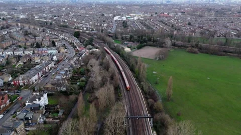 Train passing on tracks in park with wintered trees with the city in the bg Video stock 264343020