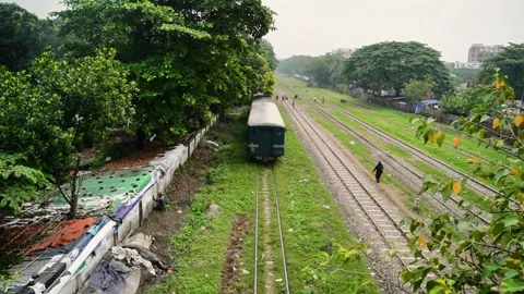 Train Passing Under Green Trees Beside Slum Area Stock Footage 320958778