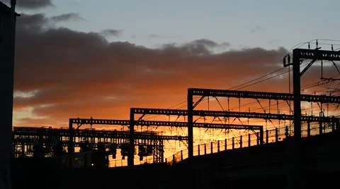 Train passing under overhead electrification and signal gantrys at sunset, uk Stock Footage 68323370