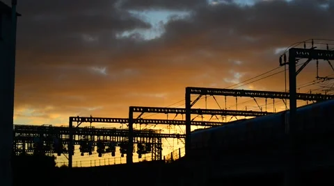 Train passing under overhead electrification and signal gantrys at sunset, uk Stock Footage 68323686