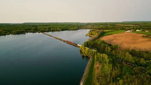 A train passing on a viaduct and surrounded by a beautiful lake and nature Stock Footage 242795196