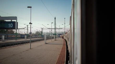 A train platform at Kelenfold stretches beneath overhead catenary wires and Stock Photos