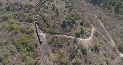 Train pulling its cargo along winding track in arid African countryside aeria Vídeo Stock 95912748