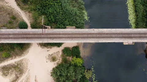 The train rides across the bridge over the river on a sunny summer day. Green Stock Footage 137178801