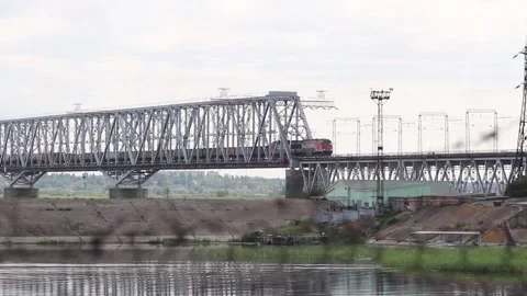 Train rides over the railway bridge over the river in summer in cloudy weather Stock Footage 138046135