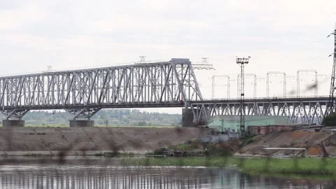 Train rides over the railway bridge over the river in summer in cloudy weather Stock Footage 138046180