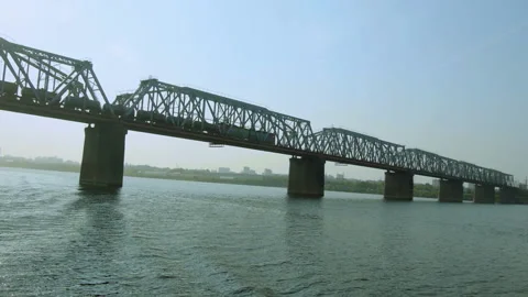 Train rides on a railway bridge over a wide river. Stock Footage 142565852