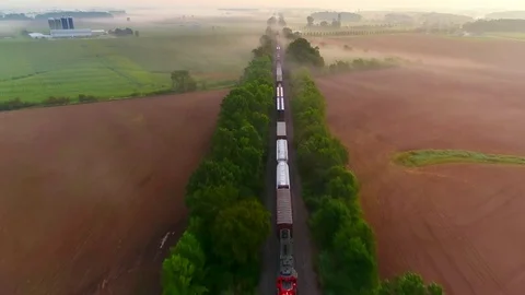 Train rolling fast through foggy countryside at dawn, aerial perspective. Stock Footage 79204269