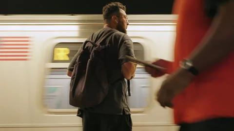 Train rushes past man with backpack on subway platform New York City New York. Stock Footage 347927014