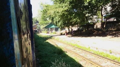 Train side in motion, hand points out window, tracks, trees, people, Yangon Видео 78077099